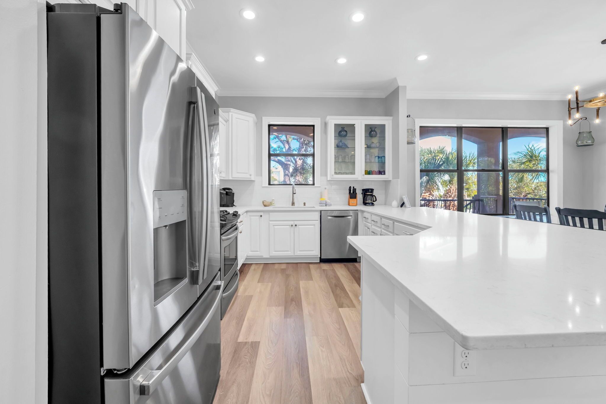 A modern kitchen with stainless steel appliances, white cabinetry, and a large island.