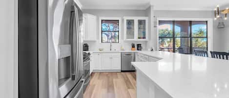 A modern kitchen with stainless steel appliances, white cabinetry, and a large island.