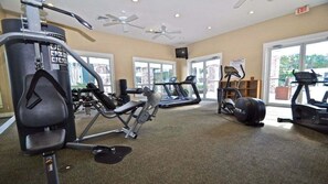 Een fitnessruimte met cardio-apparatuur, krachttrainingsmachines en een plafondventilator.