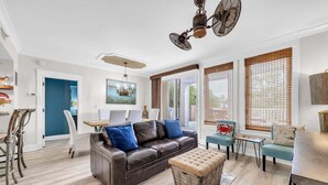 A modern living room with a brown leather sofa, blue cushions, a wooden ottoman, and a dining area with a table and chairs. - Observation Pt N 252-4 at Baytowne Warf- Pool, Gym, and Large Private Balcony! (Miramar Beach)
