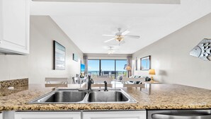 A modern kitchen with granite countertops, stainless steel appliances, and a view to the outside. - Emerald Towers West 1005- Beach Front with Gulf View Balcony! (Fort Walton Beach)