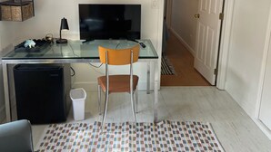 A modern living room with a glass desk, a television, a sofa, and a patterned rug.