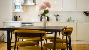 A modern kitchen with white cabinets, a central island, and yellow chairs.