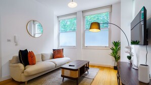 A modern living room with a sofa, coffee table, and a TV mounted on the wall.