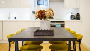 A modern kitchen with a dining table, yellow chairs, and a vase with flowers. - The Regent’s Park Nook - 1BR (Greater London)