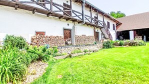 A white building with a stone foundation, a wooden staircase, and a metal railing leading to a second floor.