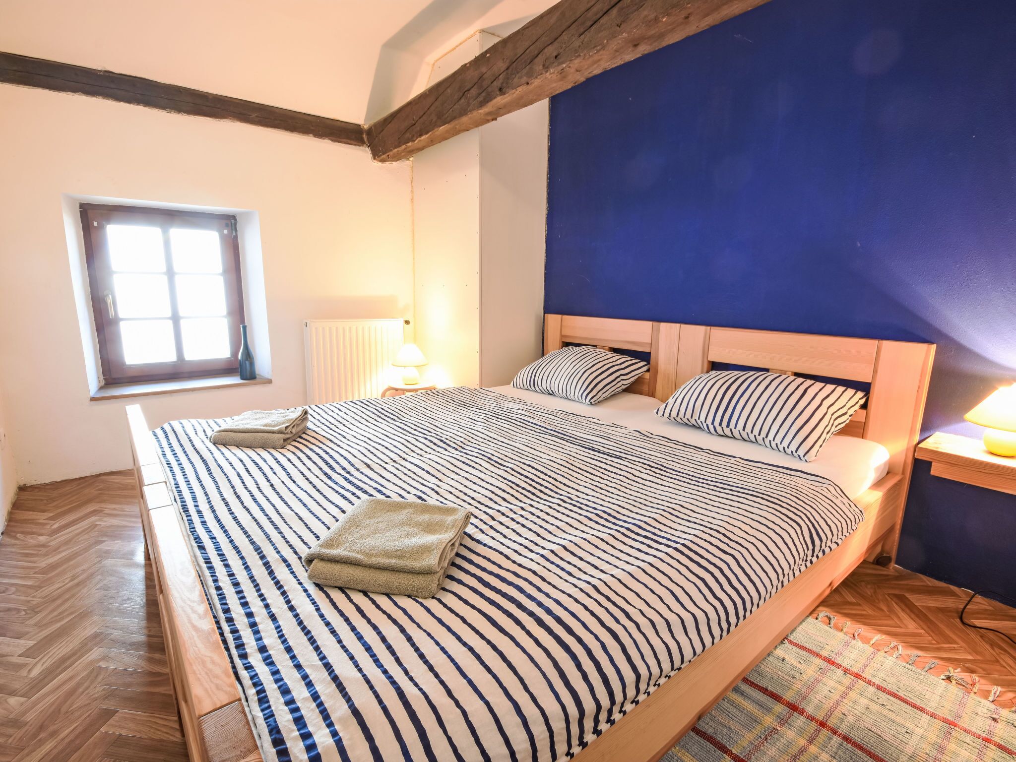 Une chambre à coucher avec un grand lit, une fenêtre et une table de chevet.