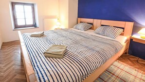 A bedroom with a large bed, a window, and a nightstand.