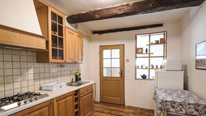 A compact kitchen with wooden cabinets, a tiled backsplash, a gas stove, and a small refrigerator.