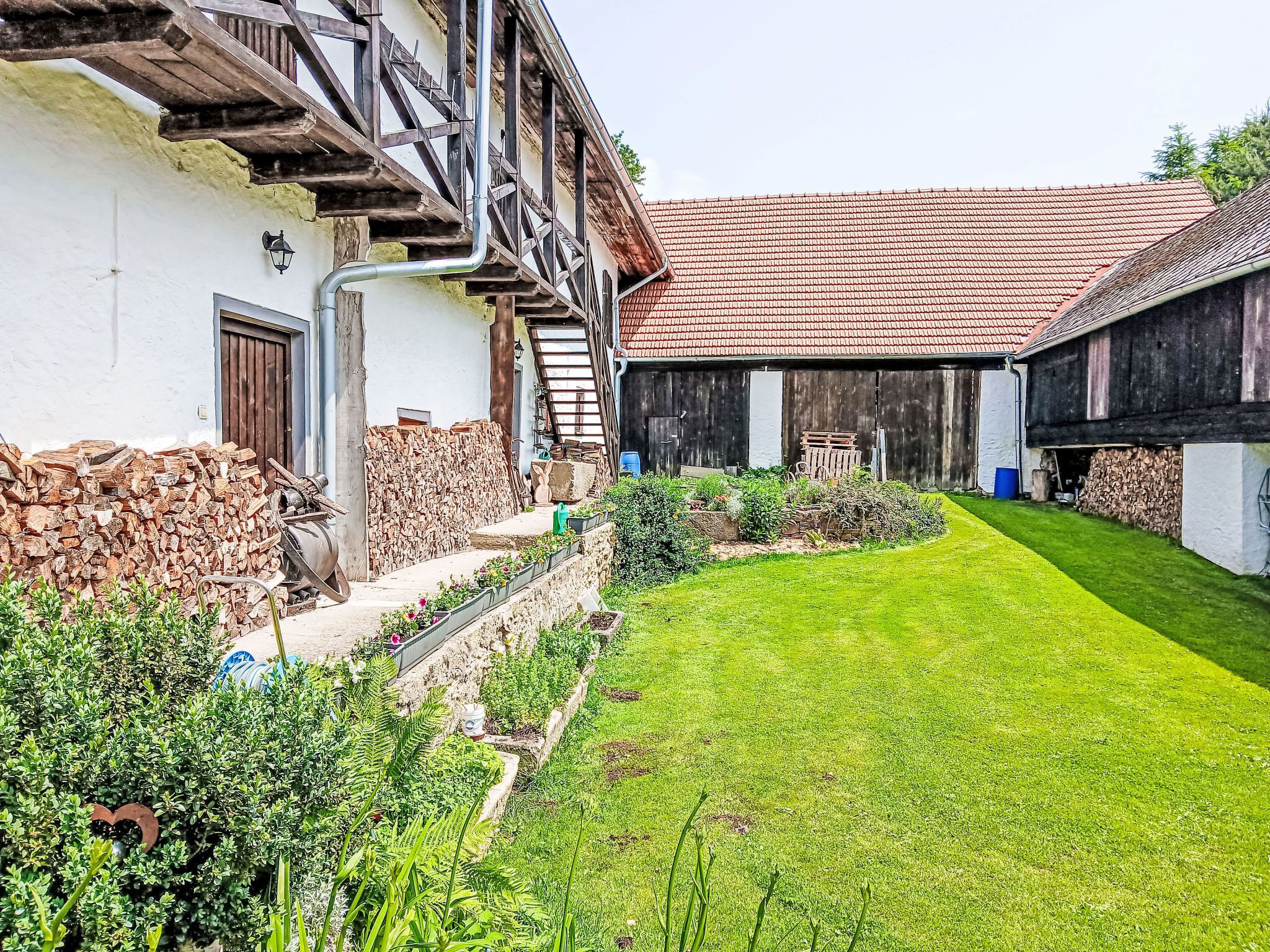 A traditional building with a sloped roof, a stone wall, and a well-maintained garden.