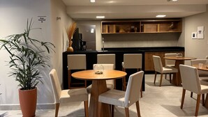 Una cocina moderna con una isla central, un comedor con una mesa redonda y sillas, y una planta en maceta.