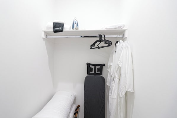 A compact bathroom with a white sink, a black ironing board, and a towel rack. - Unit 3 One BR With Queen Sofa and Bed (Washington)