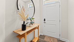 A hallway with a white door, a wooden console table with a mirror, and a vase with dried plants. - Stay Barefoot in Style – The Dye Estate 4BR Resort Home Near Beach & Golf (North Myrtle Beach)