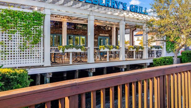 A waterfront restaurant named "Blueberry's Grill" with outdoor seating and a wooden deck. - Stay Barefoot in Style – The Dye Estate 4BR Resort Home Near Beach & Golf (North Myrtle Beach)