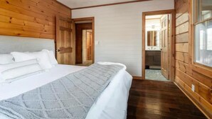 Ein Schlafzimmer mit einem großen Bett, Holzwänden und Blick ins Badezimmer.