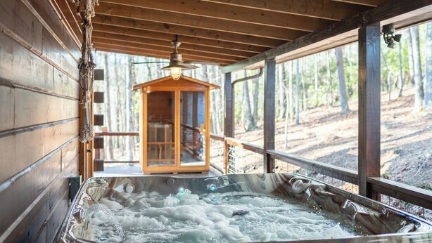 Ein Whirlpool mit Holzinnenraum und Blick auf den Wald.