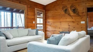 Ein gemütliches Blockhausschlafzimmer mit Holzwand, einer Couch und einem Sessel.
