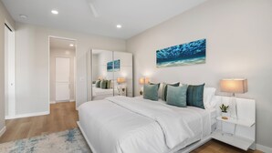 A modern bedroom with a large bed, bedside lamps, a mirror, and a wall-mounted artwork. - Condo on property at LaCosta Golf Resort & Spa with Pool 694 (Carlsbad)