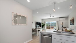 A modern kitchen with a dishwasher, a dining area with a table and chairs, and a large window offering a view of the outdoors. - Condo on property at LaCosta Golf Resort & Spa with Pool 694 (Carlsbad)
