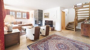 Ein großzügiges Wohnzimmer mit einer Sofagarnitur, einem Kamin, einem Fernseher und einer Treppe.