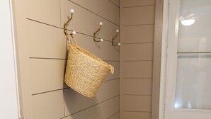 Un pasillo con un banco, una cesta fijada a la pared y una puerta con paneles de vidrio esmerilado.