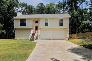 A two-story house with a front entrance, a covered porch, and a driveway leading to a garage.