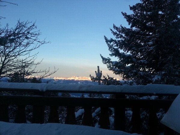 A snowy landscape with a clear sky, a wooden railing, and snow-covered trees.