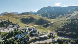 A mountainous town with a mix of modern and traditional buildings, a central roundabout, and a road leading to the mountains. - Unusual chalet, 2 ppl, terrace with mountain view. (Chamrousse)