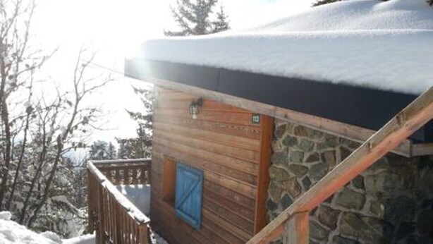 A wooden cabin with a stone wall and a wooden deck, surrounded by snow. - Unusual chalet, 2 ppl, terrace with mountain view. (Chamrousse)