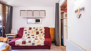 A compact room with a bed, a small table, a wardrobe, and a wall-mounted air conditioner. - Nice Apt near the slopes for 4 pers (Morillon)
