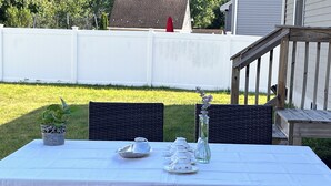 An outdoor dining area with a table set for four, surrounded by wicker chairs. - New Home • 8 Miles to LBI .BBQ. Family friendly.  (Stafford Township)