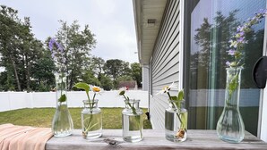 A wooden table with five glass vases containing flowers and greenery. - New Home • 8 Miles to LBI .BBQ. Family friendly.  (Stafford Township)