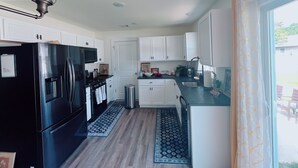 A modern kitchen with white cabinets, a black refrigerator, stainless steel appliances, and a blue patterned rug. - New Home • 8 Miles to LBI .BBQ. Family friendly.  (Stafford Township)