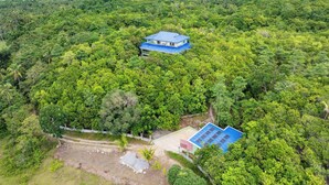 An aerial view of a property surrounded by dense forest, featuring a main building with a blue roof and a smaller structure with a blue roof. - Villa Jolam - Family Haven in an Island Paradise - Camotes (Poro)