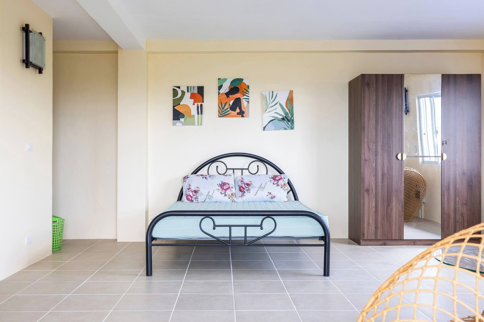 A bedroom with a bed, a wardrobe, and three abstract paintings on the wall.