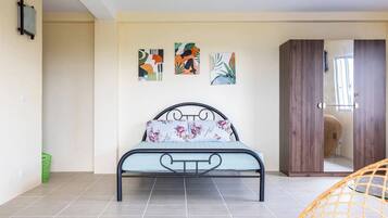 A bedroom with a bed, a wardrobe, and three abstract paintings on the wall.