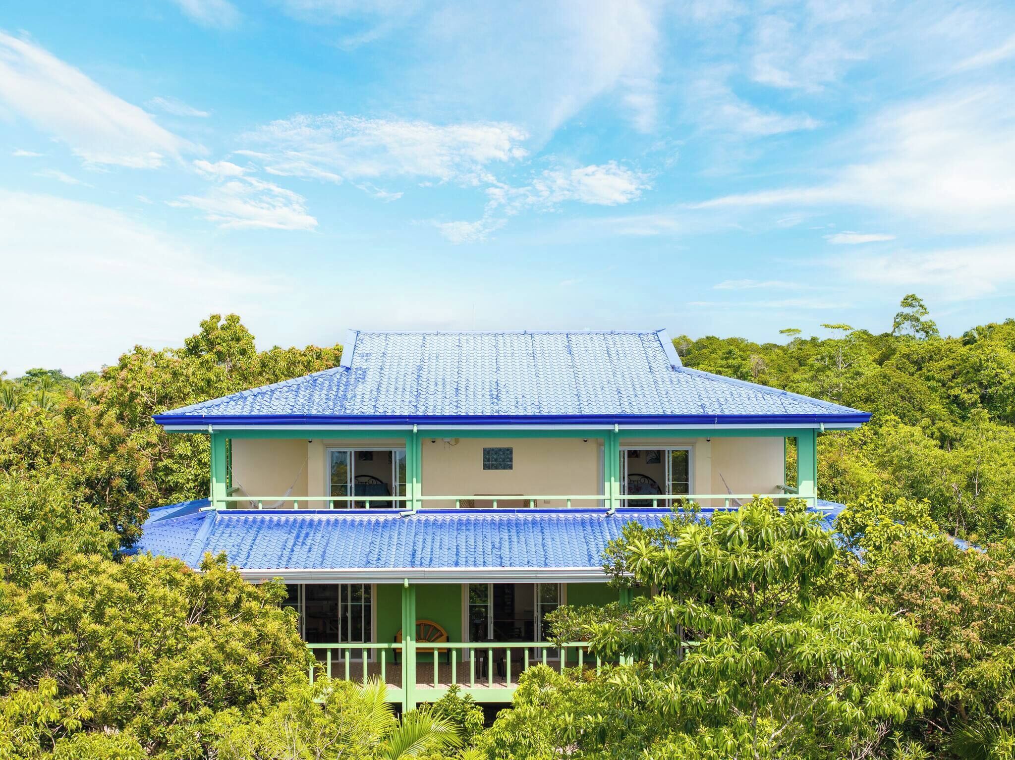 Un edificio su due piani con tetto blu, immerso nel verde.
