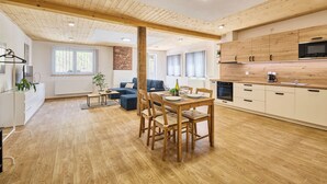 Un vaste espace de vie doté d’un plancher en bois, d’une table à manger et d’une cuisine avec des armoires blanches et un comptoir en bois.