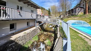 Un bâtiment doté d’un balcon, d’un petit ruisseau et d’une piscine.