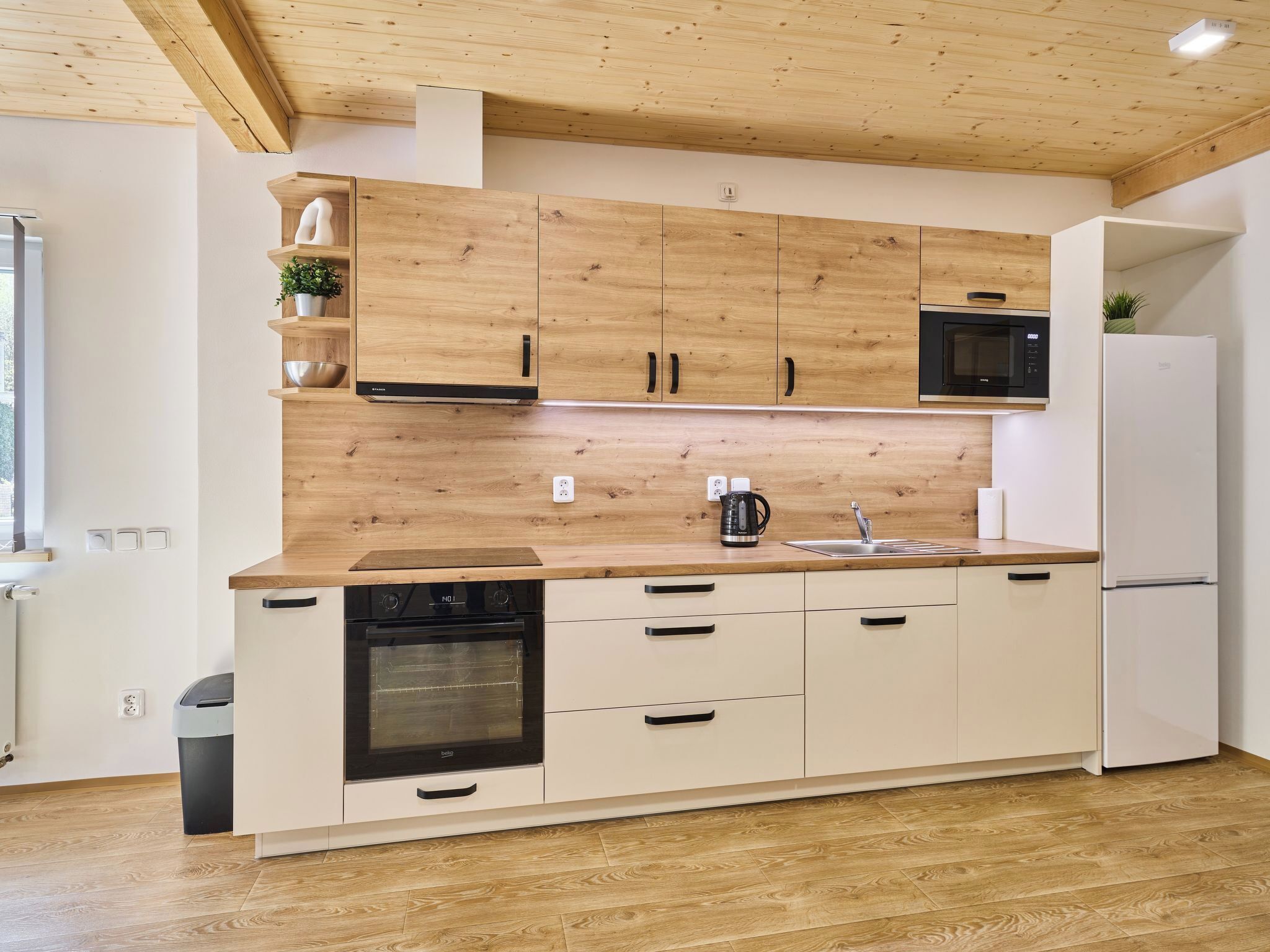 Une cuisine moderne avec des meubles en bois, un four à micro-ondes encastré, un lave-vaisselle et un évier.