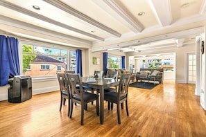 A spacious living area with a dining table, chairs, and a sofa. - Seabreeze Escape | Beach Steps & 4th of July (Long Beach)