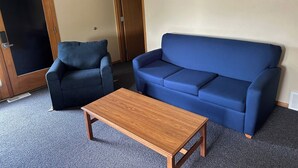 A living room with a blue sofa, a matching armchair, and a wooden coffee table. - Apartment Centrally Located (Plymouth)