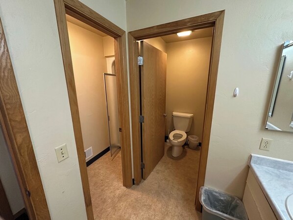 Ein kleines Badezimmer mit Toilette, Mülleimer und Spiegel an der Wand.