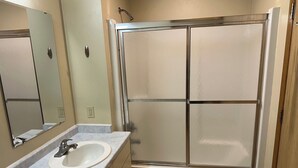 A bathroom with a sink, mirror, and a shower enclosure. - Apartment Centrally Located (Plymouth)