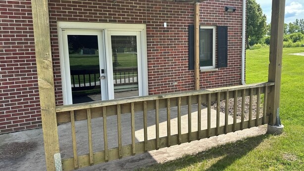 A brick building with a wooden porch and a metal railing. - Apartment Centrally Located (Plymouth)