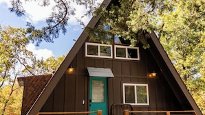 A wooden cabin with a steep roof, a front door, and a staircase leading to the entrance.