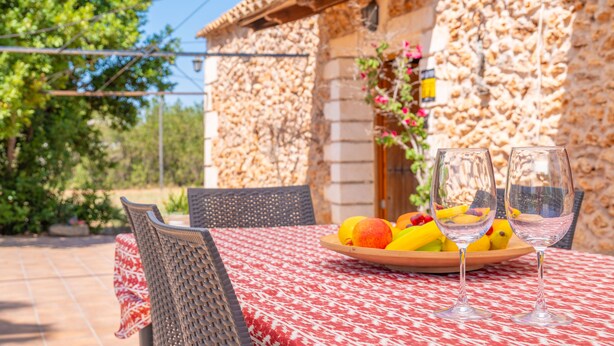 A table with a fruit bowl and two wine glasses, set outdoors with a stone building in the background. - SON FIGUEROLA - Beautiful villa with private pool and free Wi-Fi in Inca (Inca)