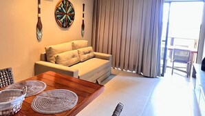 A modern living room with a sofa, dining table, and decorative wall art. - ECO RESORT | Carneiros Beach Right on the sand next to the Carneiros Church (Tamandaré)
