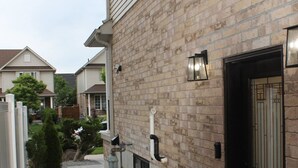 A residential building with a brick facade, a tiled walkway, and a small garden area.