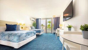 A hotel room with two beds, a desk, a chair, a TV, and a balcony with a view of palm trees.